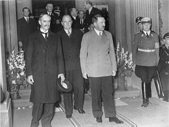 Unsmiling, Chamberlain (left) and Hitler leave...